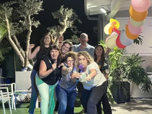 חבורת חברים שרה ומצביעה למצלמה במסיבה בחצר