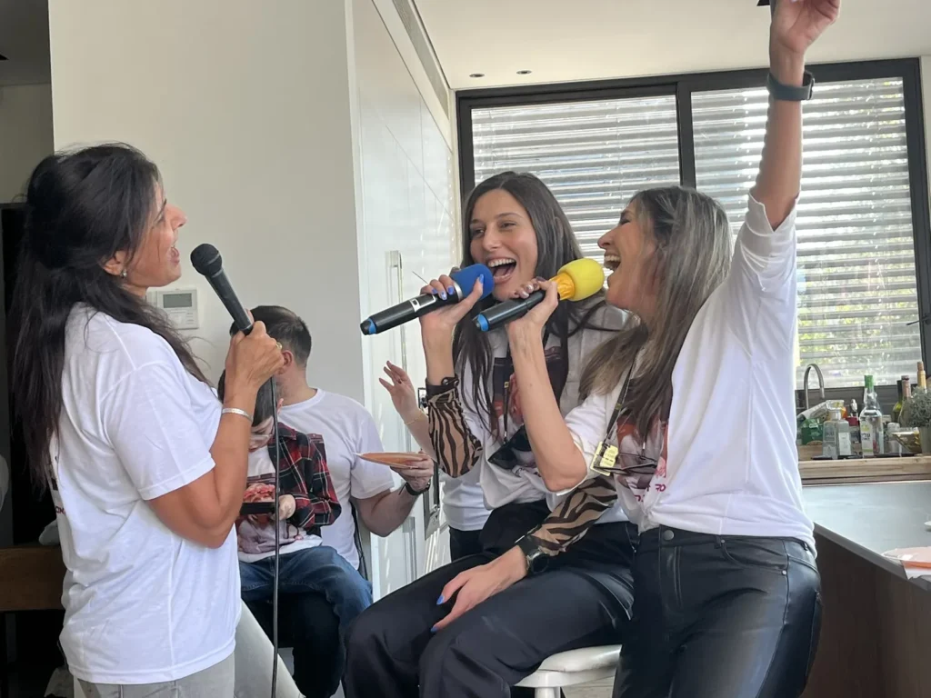 שלוש נשים שרות וצוחקות במיקרופונים ביום הולדת משפחתי
