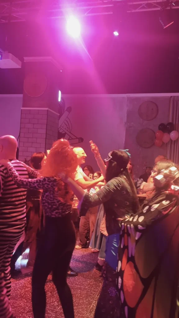 אורחים בתחפושות רוקדים בתאורה ורודה