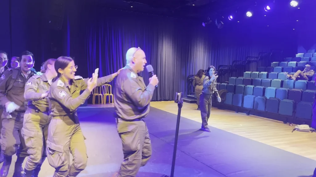 חיילים וחיילות שרים ורוקדים על במה באולם