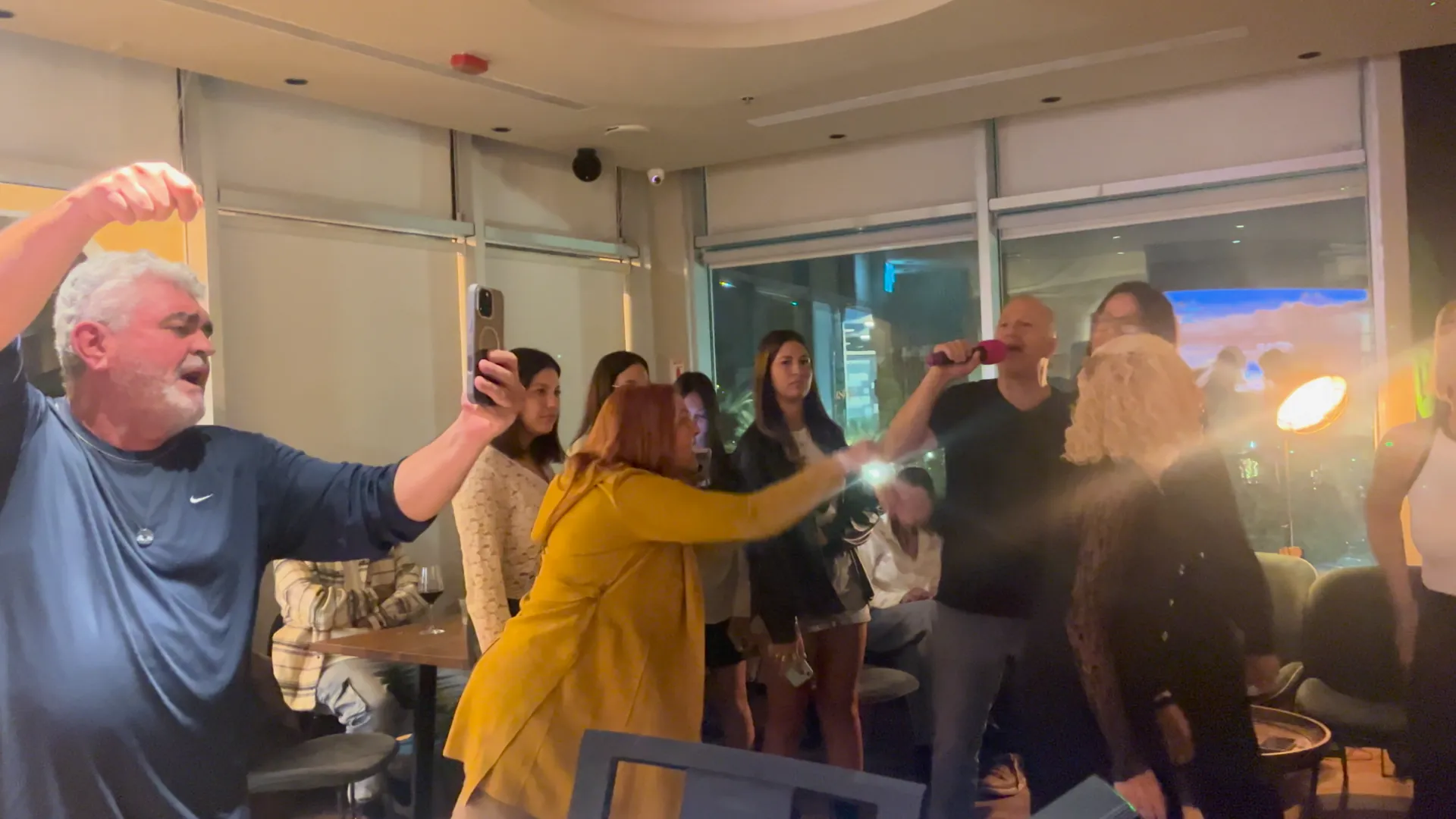 אורח ואורחת רוקדים בידיים מונפות בערב קריוקי